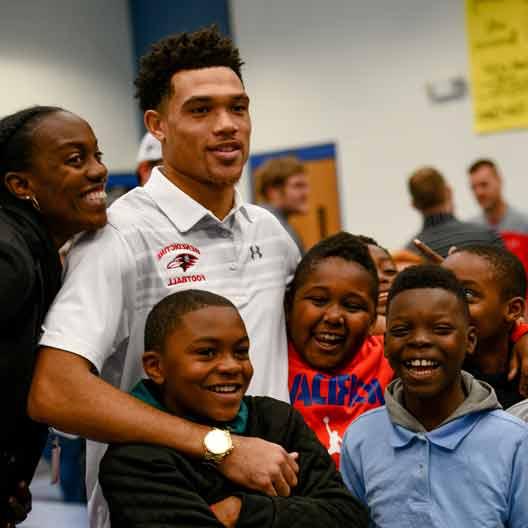 A student poses for a photo with multiple children